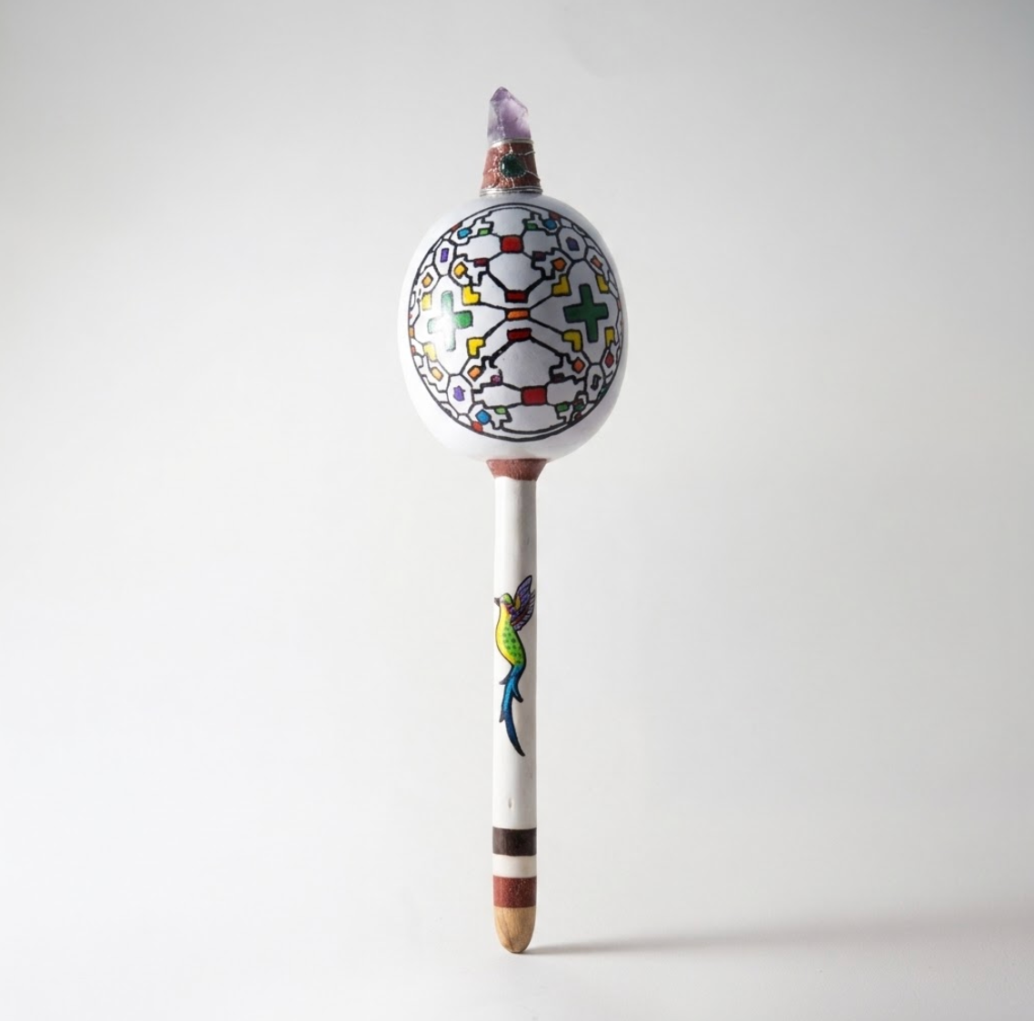 Weiße schamanische Rassel mit bunten geometrischen Mustern, Vogelmotiv und Amethyst-Spitze – handgefertigtes Ritualinstrument aus Peru