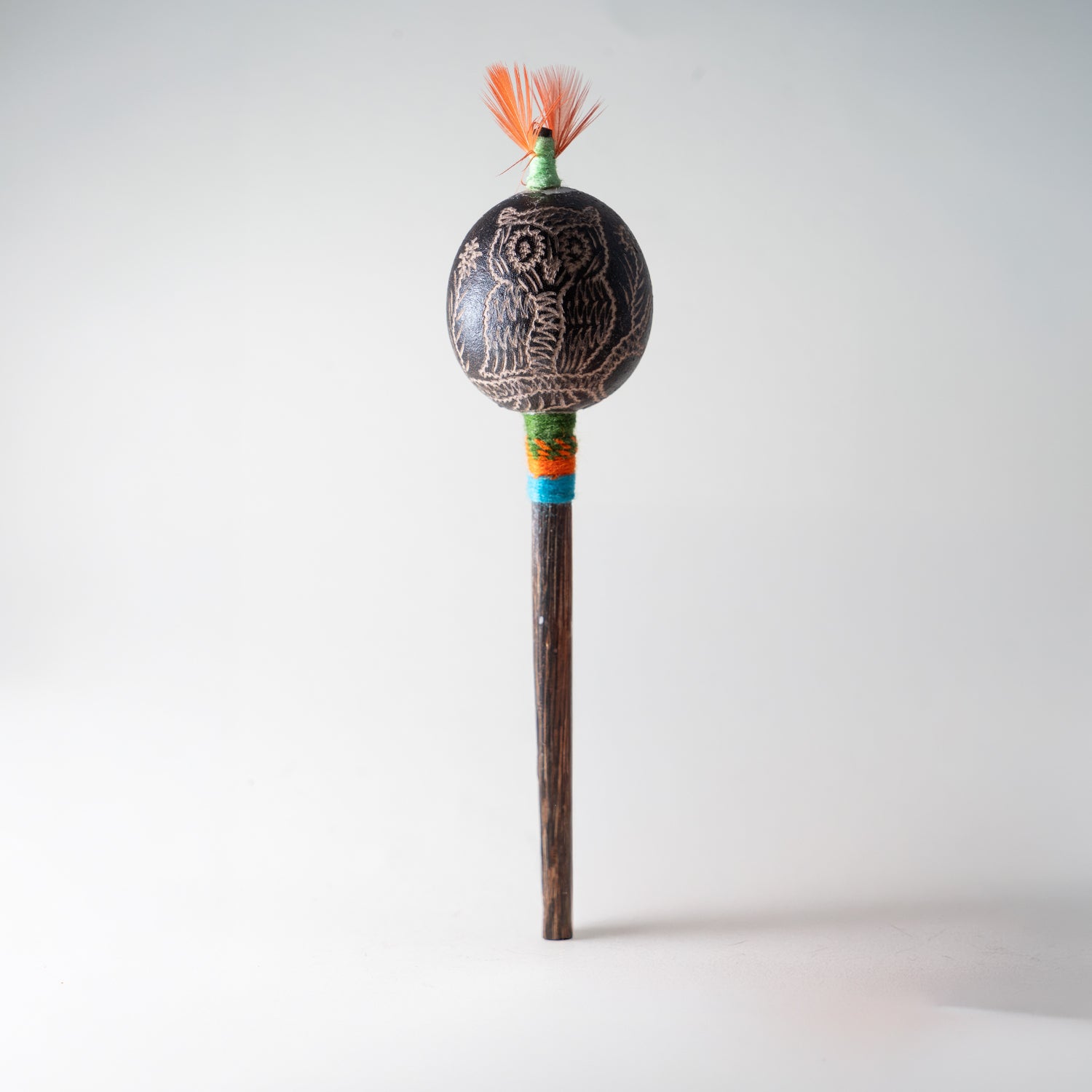 Schamanische Rassel mit eingravierter Eule, orangem Federschmuck und türkis-grünem Griffband – handgefertigtes Eulenmotiv Ritualinstrument